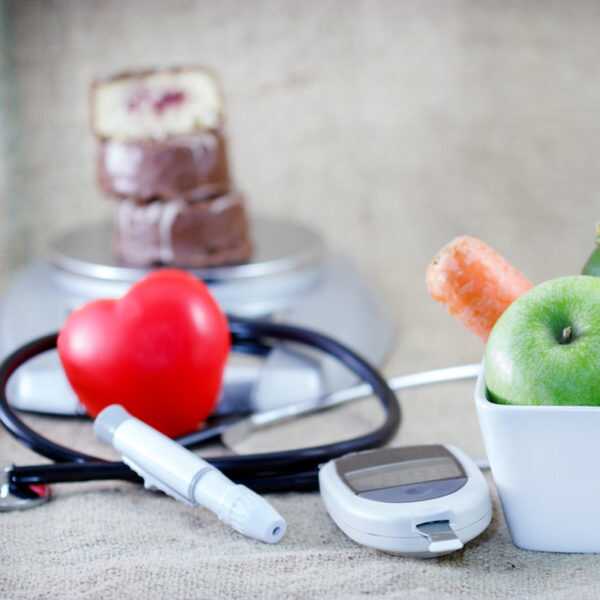 A bowl of fruit, a stethoscope and a EpiPen on a table.