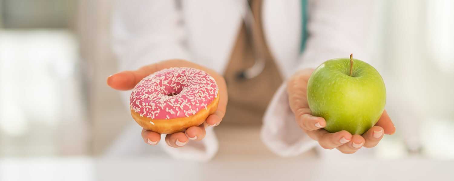 A doctor holding an apple and a donut.
