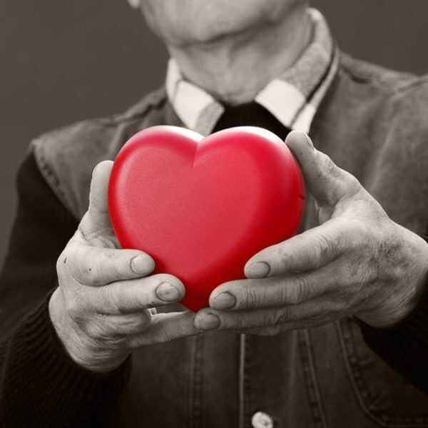 An older man holding a red heart in his hands.